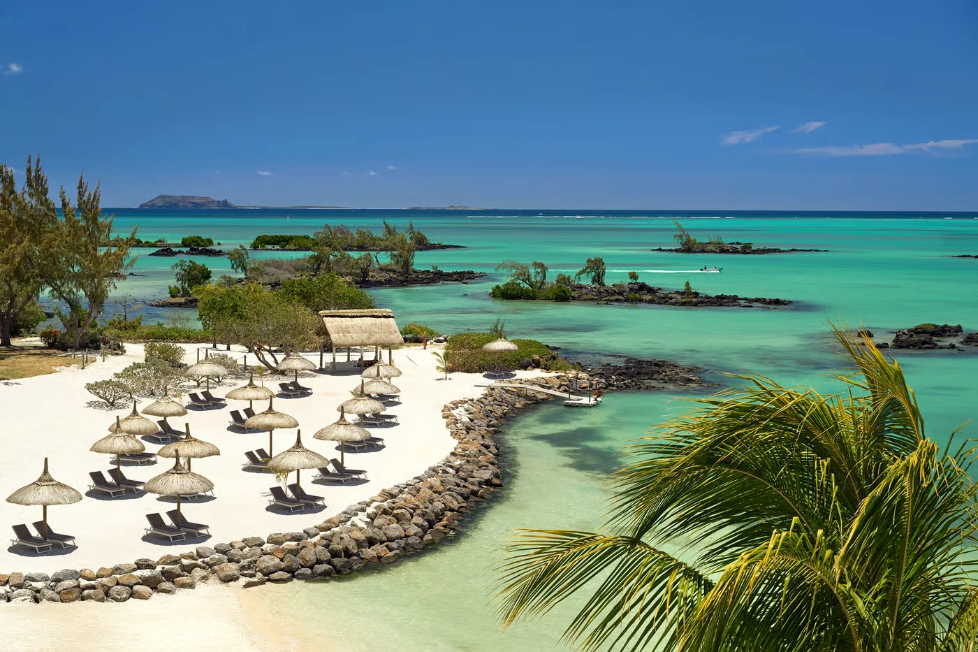 Palm-fringed lagoon beach with thatched parasols and turquoise water in Mauritius