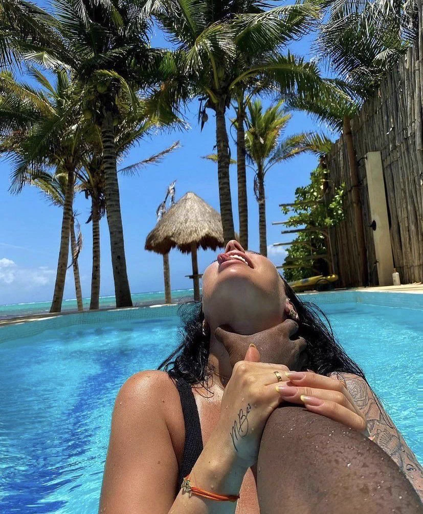 Woman relaxing in a pool beneath palm trees