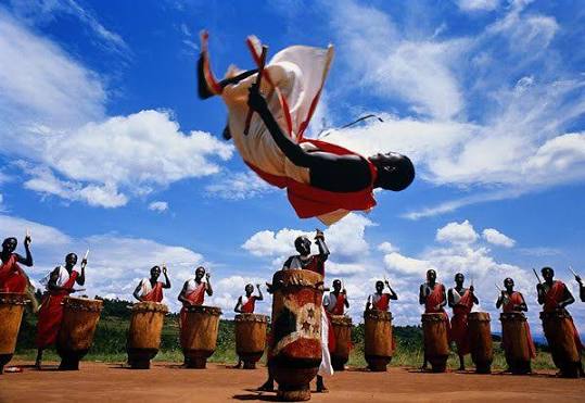 Traditional Rwandan drummers and a dancer leaping in performance
